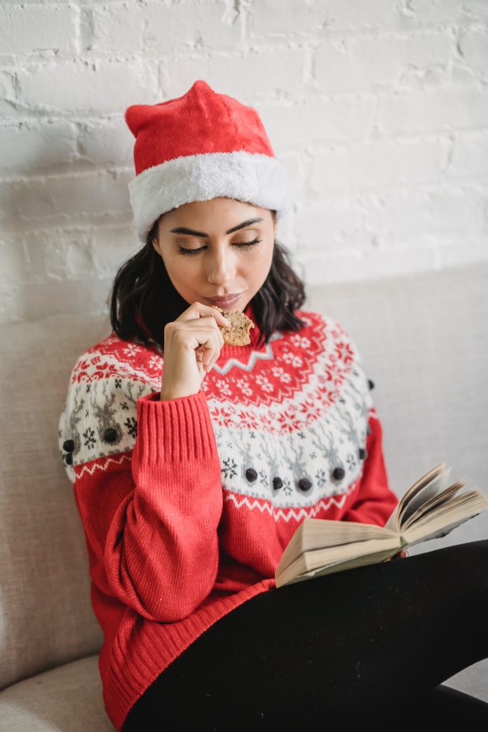 Young woman in Christmas clothes with book at home creidt: pexels-julia-larson